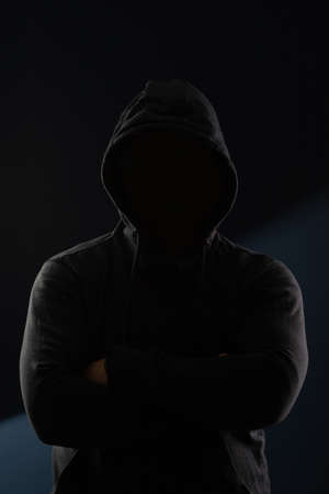 Scary man hiding in the shadows, with the face and identity hidden with the hood. Concept for fear, mystery, danger, crime, stalkerの写真素材