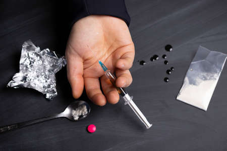 Drug addict reaches for another dose of drug. Concept of addiction, antidrug. International Day...