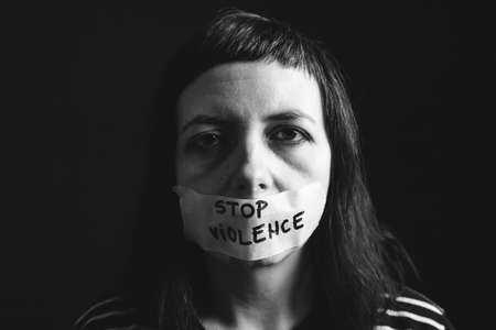 Women violence and abused concept. Stop domestic violence against women and human trafficking.Woman with tape on mouth and stop violence textの写真素材