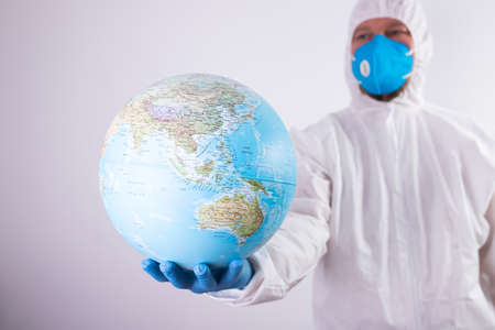 World epidemic danger concept. Male doctor man in medical face mask and gloves protecting planet...