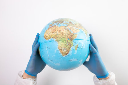 World epidemic danger concept. Hands of doctor in medical face mask and gloves protecting planet Earth.の写真素材