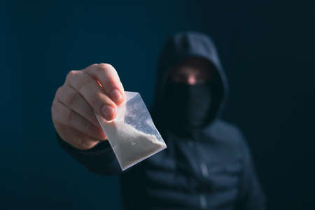 Hand of addict man holding a dose of cocaine or heroine. Concept of drug dealer, drug trafficking,...