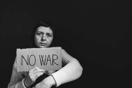Sad woman calls to Stop war in Ukraine, raises banner with inscription No war.の写真素材