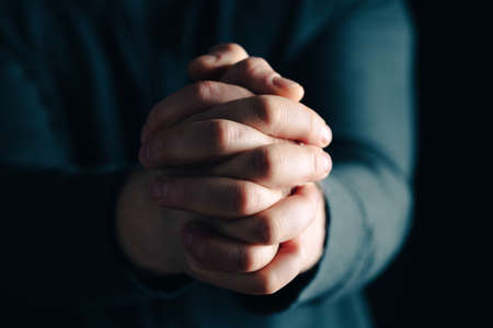 Praying hands with faith in religion and belief in God on dark background. Power of hope or love and devotion.の写真素材