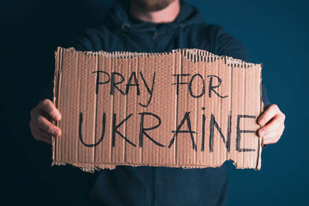Man holding Pray for Ukraine banner. Concept symbol of help support and no war in the country of Ukraine.の写真素材