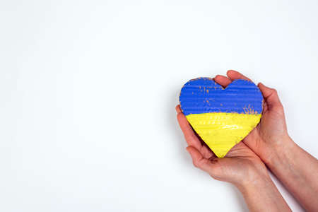 Heart shaped flag of Ukraine in female hands. The concept of solidarity with the citizens of Ukraine.の写真素材