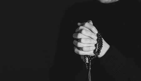Religious young woman praying to God, on dark background.の写真素材