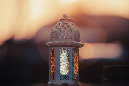 Ramadan Kareem background. Ornamental Arabic lantern glowing at night and the holy book of Quran.の写真素材