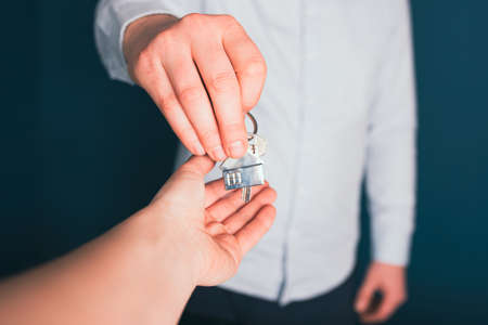 Businessman hands over house keys to client. The concept of a realtor, mortgage, your house, home loan.の写真素材