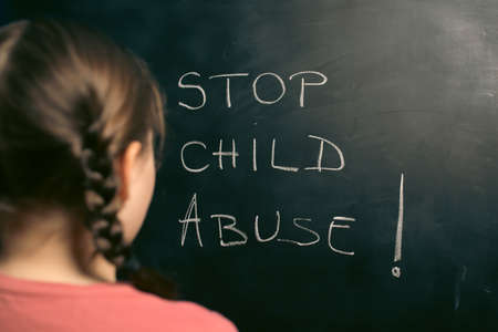 Child violence and abused concept. Little sad girl with Stop child abuse text writted on a blackboardの写真素材