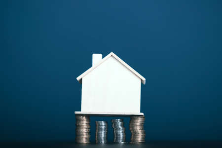 Coin stack with house model on table with copy space. Realtor, mortgage, your house, home loan...