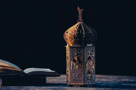 Ramadan Kareem background. Ornamental Arabic lantern glowing at night and the holy book of Quran.の写真素材