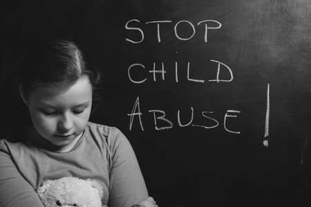 Child violence and abused concept. Little sad girl with Stop child abuse text writted on a blackboardの写真素材