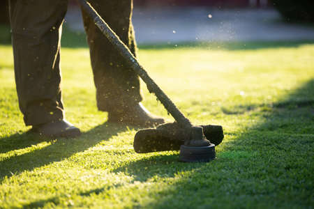 Mowing the grass with a lawn mower. Garden work concept background.