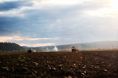 Cultivated field, agronomy, farming concept. Farmer in tractor preparing land with seedbed...