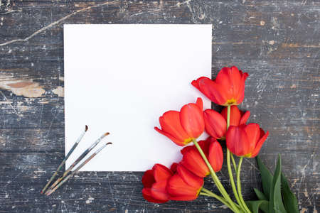 Creative spring concept made with paint brush and red tulip flowers on wooden background.の写真素材