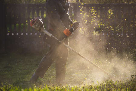 Mowing the grass with a lawn mower. Garden work concept background.