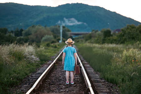 Retro styled photo of little girl with old luggage at the railways