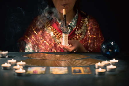Fortune teller with tarot cards on table near burning candles.Tarot cards spread on table with crystal ball.Forecasting concept.の写真素材