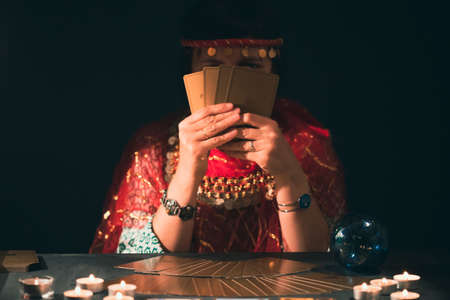Fortune teller with tarot cards on table near burning candles.Tarot cards spread on table with crystal ball.Forecasting concept.の写真素材