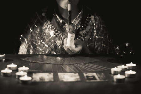 Fortune teller with tarot cards on table near burning candles.Tarot cards spread on table with crystal ball.Forecasting concept.の写真素材