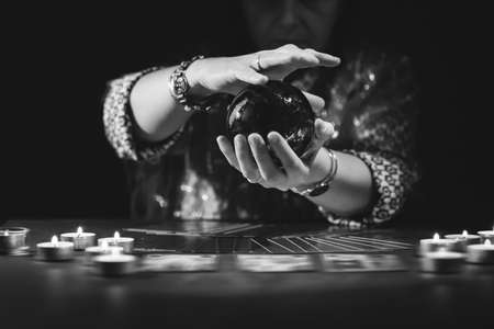Fortune teller with tarot cards on table near burning candles.Tarot cards spread on table with crystal ball.Forecasting concept.の写真素材