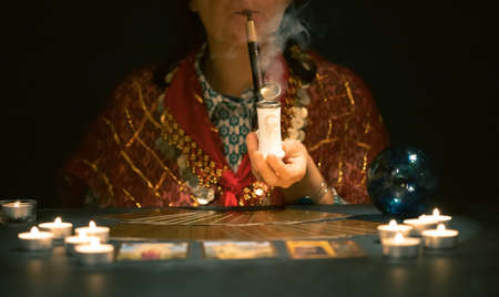 Fortune teller with tarot cards on table near burning candles.Tarot cards spread on table with crystal ball.Forecasting concept.の写真素材