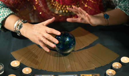 Fortune teller with tarot cards on table near burning candles.Tarot cards spread on table with crystal ball.Forecasting concept.の写真素材