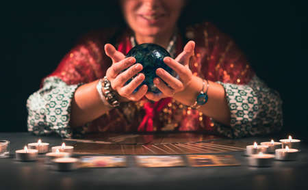 Fortune teller with tarot cards on table near burning candles.Tarot cards spread on table with crystal ball.Forecasting concept.の写真素材
