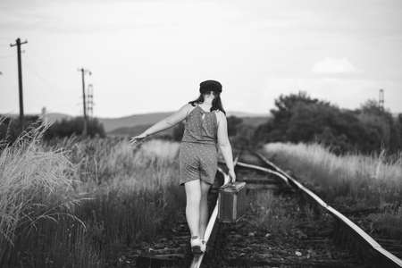Retro styled photo of little girl with old luggage at the railwaysの写真素材