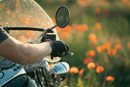 Motorcycle closeup in magic sunset in the poppy field. Travel and sport, speed and freedom conceptの写真素材