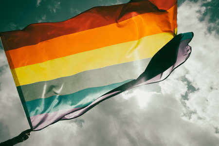 Bright rainbow LGBT flag fluttering against blue sky. LGBT community, happiness, freedom and love concept for same sex couples.の写真素材