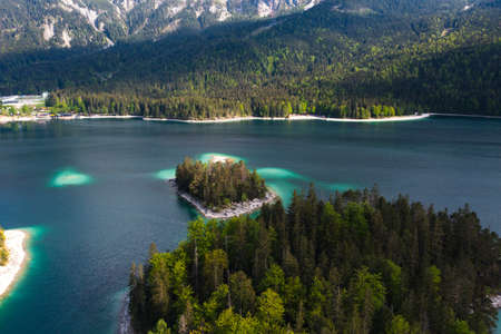 Aerial landscape of Eibsee Lake with turquoise water in front of Zugspitze summit,...