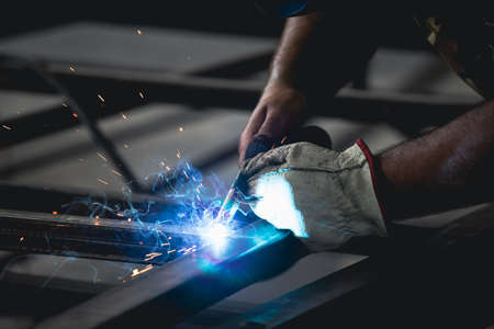 Handyman performing welding and grinding at his workplace in the workshop, while the sparks fly all...