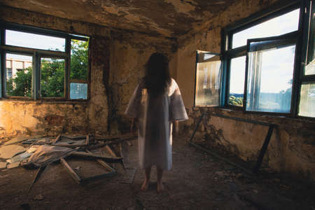 Ghost in abandoned, haunted house. Horror scene of scary spirit of a woman, halloween concept.の写真素材