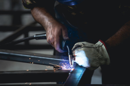 Handyman performing welding and grinding at his workplace in the workshop, while the sparks fly all...