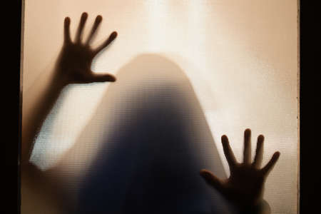 Horror ghost figure behind the matte glass. Halloween festival concept.