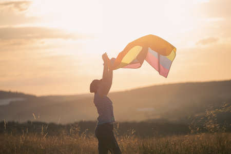 Woman holding a Gay Rainbow Flag in magic sunset. Happiness, freedom and love concept for same sex...