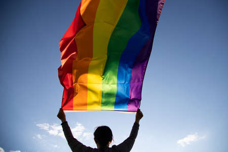 Woman holding a Gay Rainbow Flag. Happiness, freedom and love concept for same sex couples