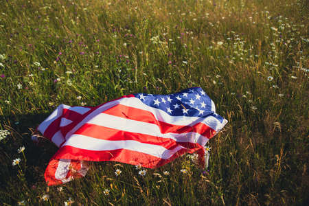 Close up view of USA flag that lying down on summer meadow. 4th of July - Independence day.