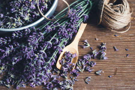Top view of a bowl and wooden scoop of fresh lavender flowers on wooden rustic table. Aromatherapy, spa, massage concept.の写真素材