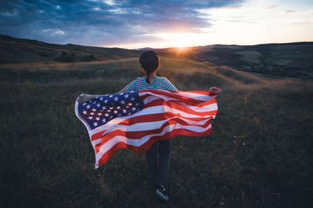 Young woman holding american USA flag. Independence Day or traveling in America concept.の写真素材