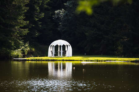 White wedding pavilion altar next to a small lakeの写真素材
