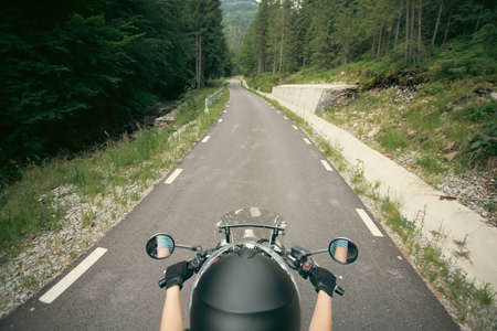 Biker girl on a motorcycle on summer forest road. Travel and sport, speed and freedom concept.の写真素材
