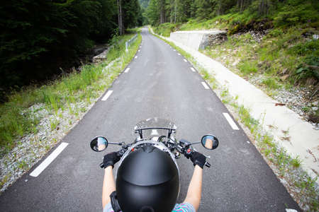 Biker girl on a motorcycle on summer forest road. Travel and sport, speed and freedom concept.の写真素材