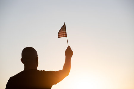 Man holding american USA flag in the sunset. Independence Day or traveling in America concept.の写真素材