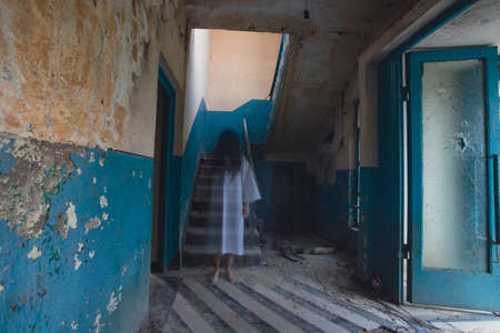 Ghost in abandoned, haunted house. Horror scene of scary spirit of a woman, halloween concept.の写真素材