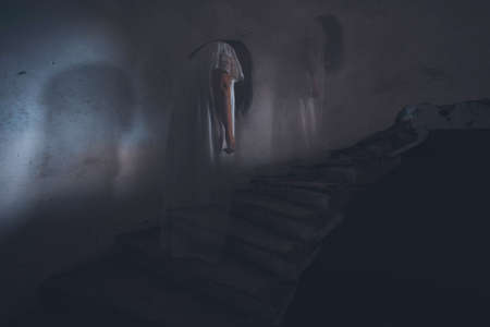 Ghost in abandoned, haunted house. Horror scene of scary spirit of a woman, halloween concept.の写真素材