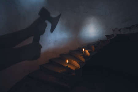 Ghost in abandoned, haunted house. Horror scene of spooky silhouette holding old axe, halloween concept.の写真素材