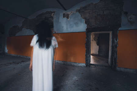 Ghost in abandoned, haunted house. Horror scene of scary spirit of a woman, halloween concept.の写真素材